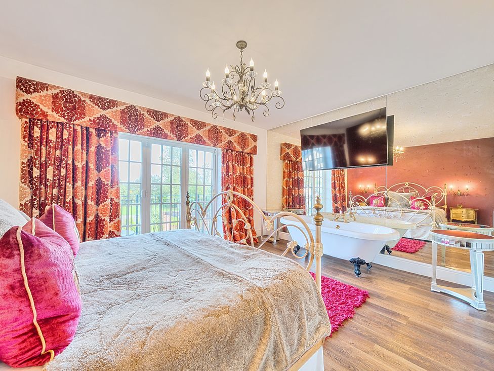 A bedroom with a bed, television, and bathtub at Moor End Manor in Stalmine