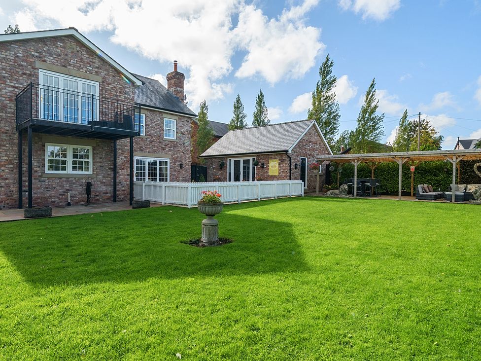 A garden with a house, lawn and outdoor seating area at Moor End Manor in Stalmine