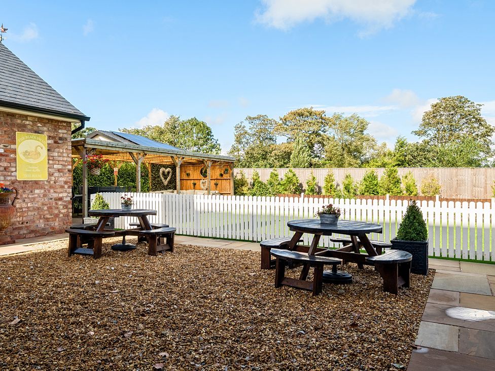A garden with a wooden table and benches at Moor End Manor in Stalmine