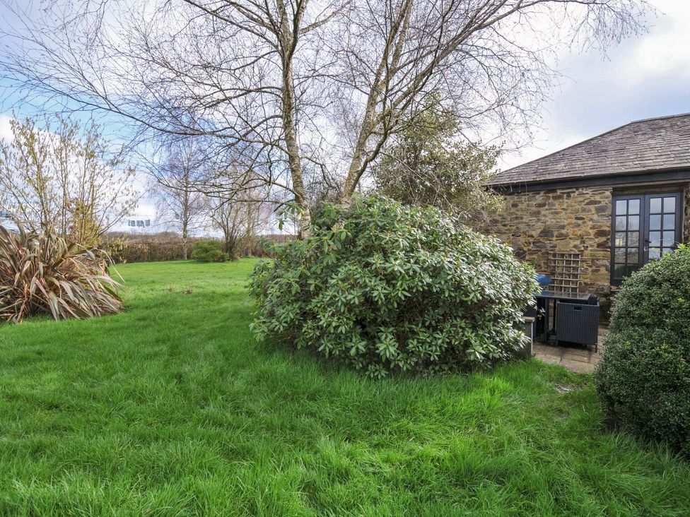 A garden with grass, bushes, and a house at Lazy Hare at Jen's Orchard St Giles On The Heath
