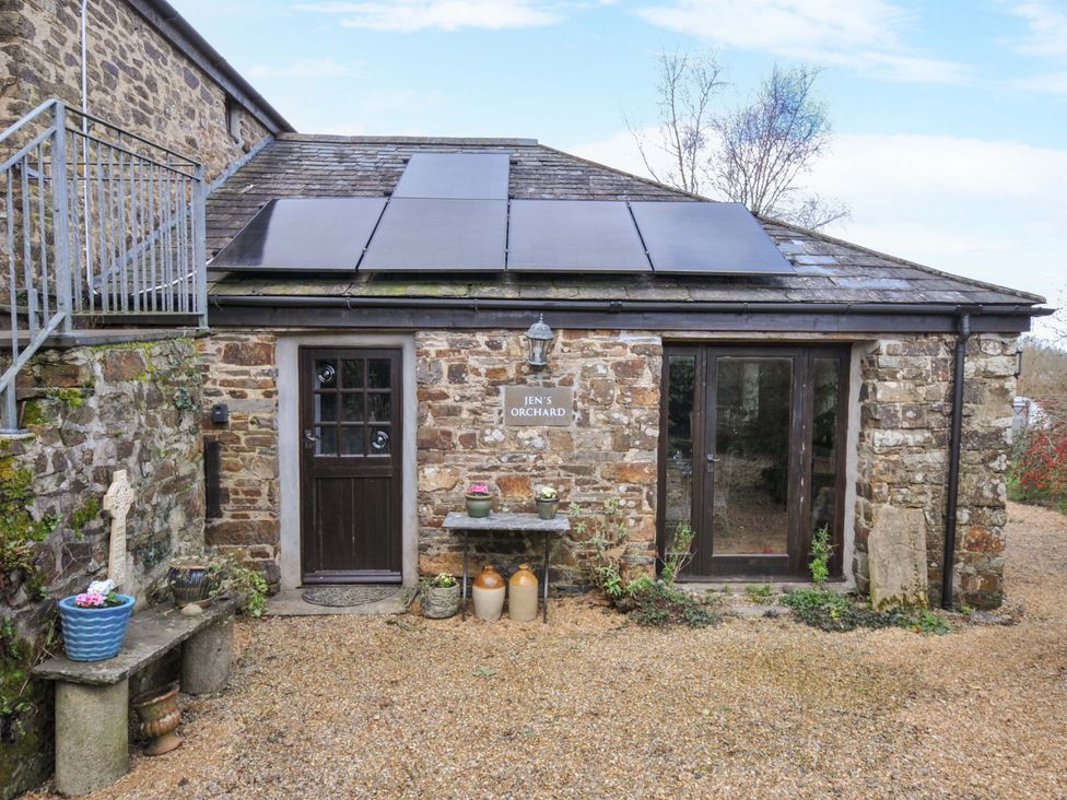 An outdoor view of a stone cottage with solar panels at Lazy Hare at Jen's Orchard St Giles On The Heath