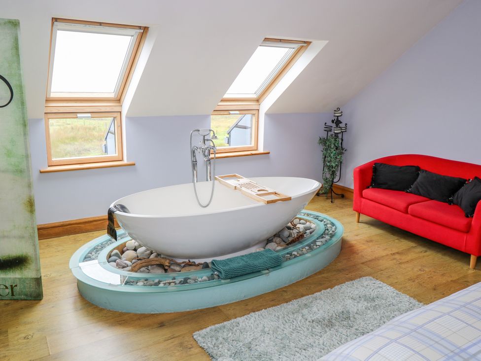 A bathroom with a bathtub and sofa at Ocean Sail House Termon near Dungloe County Donegal