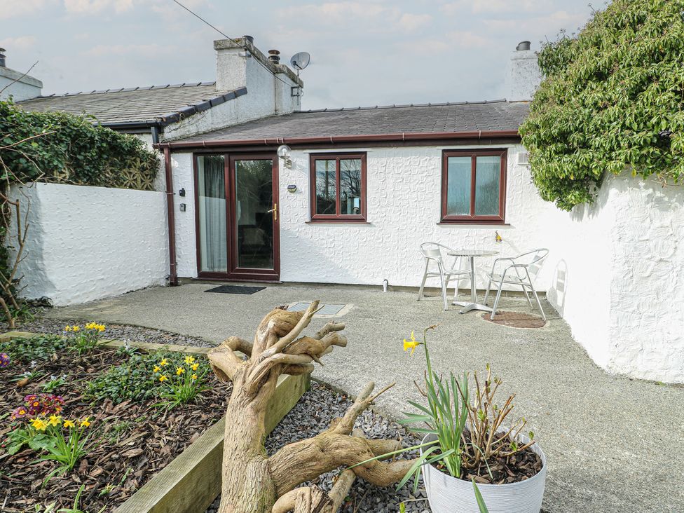 An outdoor area with a house and table with chairs at Bwthyn in Moelfre