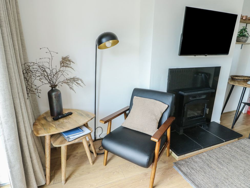 A living room with an armchair and lamp at Bwthyn in Moelfre