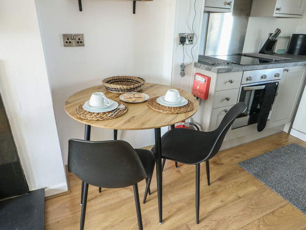 A kitchen with a table and chairs setup at Bwthyn Moelfre