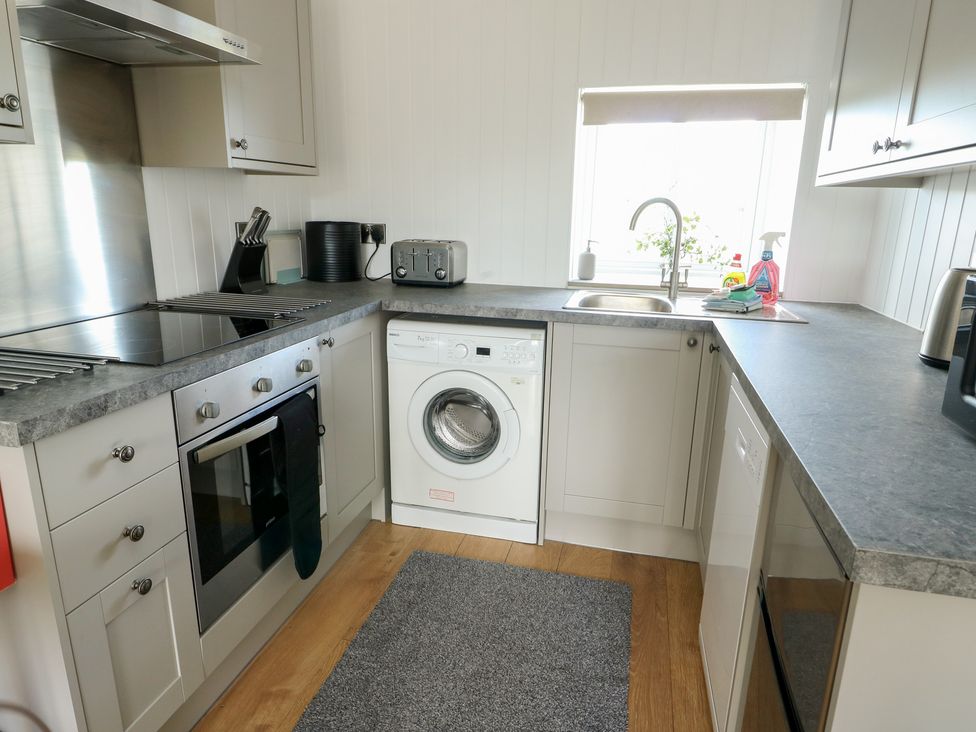 A kitchen with appliances and a washing machine at Bwthyn in Moelfre