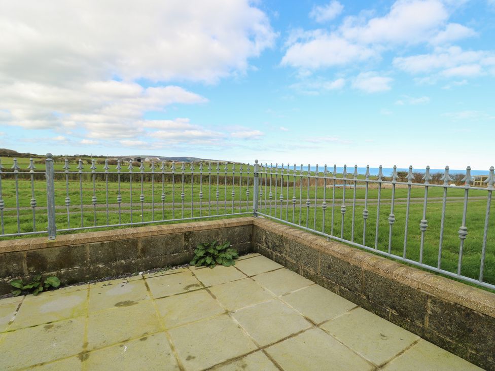 An outdoor area with a fence and a stone wall at Bwthyn in Moelfre