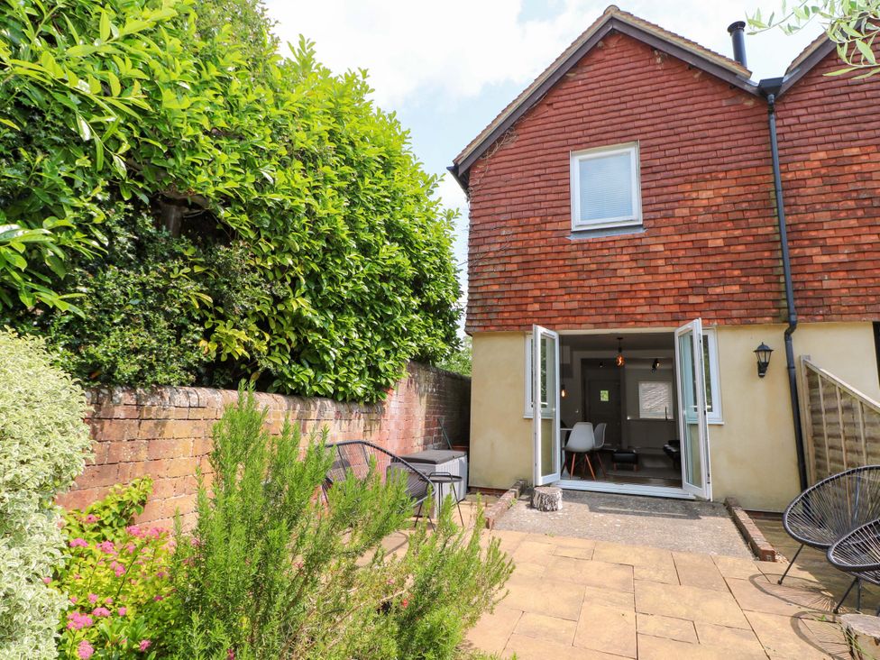 A garden with a house and patio furniture at 2A The Mews Langstone