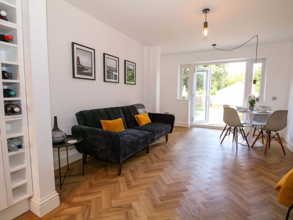 A living room with a sofa and dining area at 2A The Mews in Langstone
