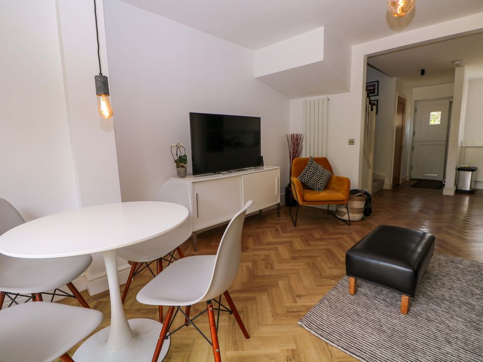 A living room with a table, chairs, and a television at 2A The Mews in Langstone
