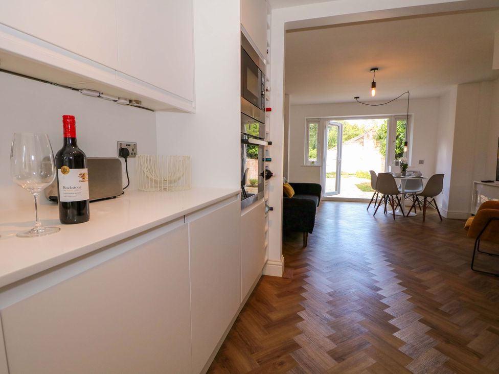 A kitchen with wine bottle and glasses near an open dining area at 2A The Mews in Langstone