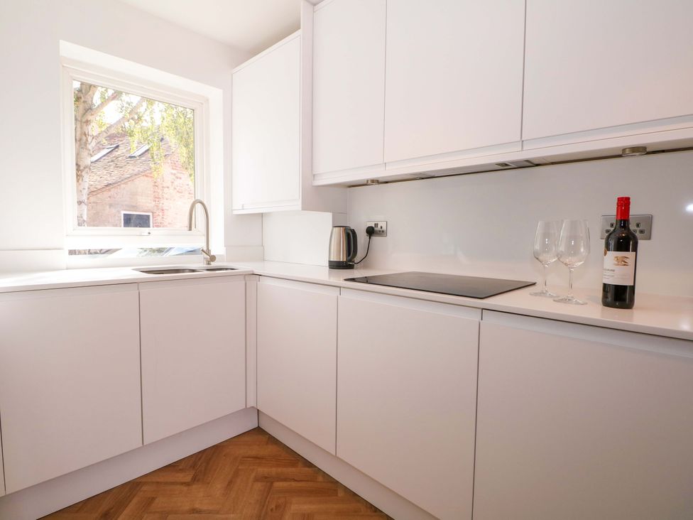 A kitchen with a sink, kettle, wine glasses and a wine bottle at 2A The Mews, Langstone