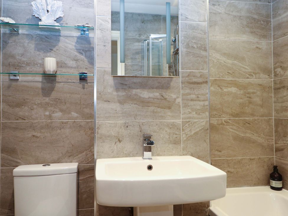 A bathroom with a sink, toilet, and shower at 2A The Mews, Langstone