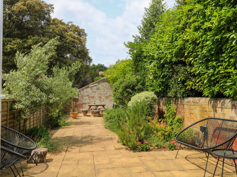 A garden with a table and chairs surrounded by plants at 2A The Mews Langstone