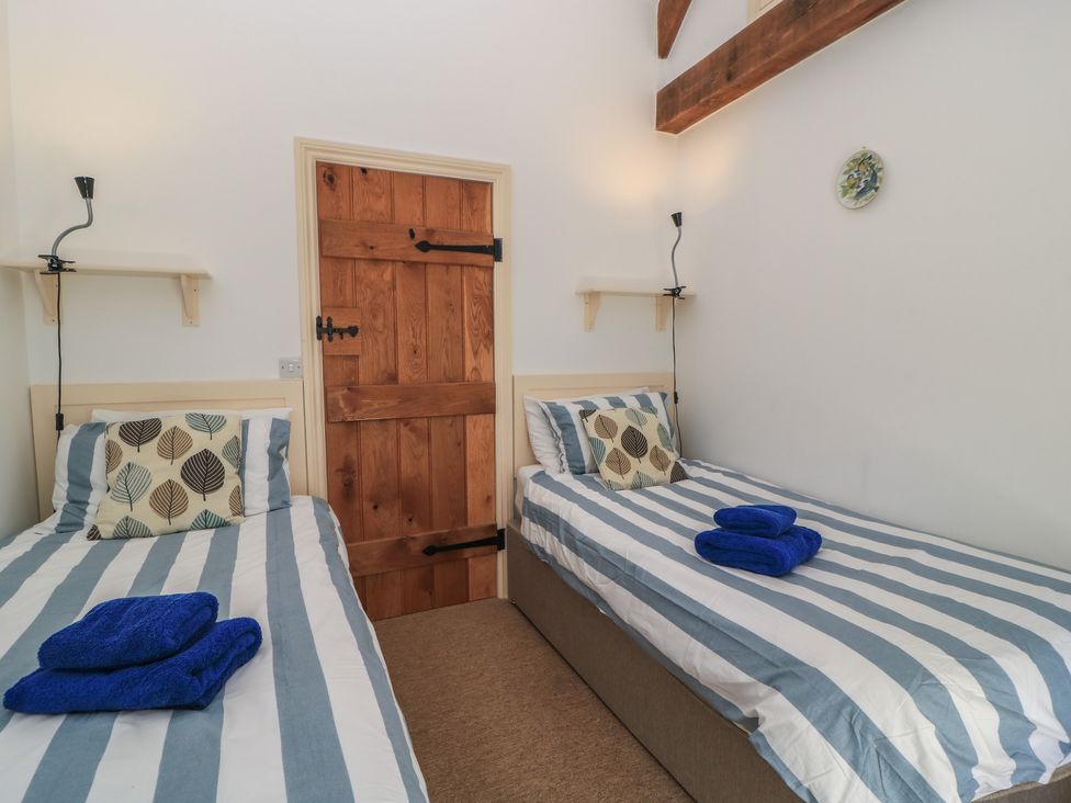 A bedroom with two beds and a wooden door at Dale Barton in Wells