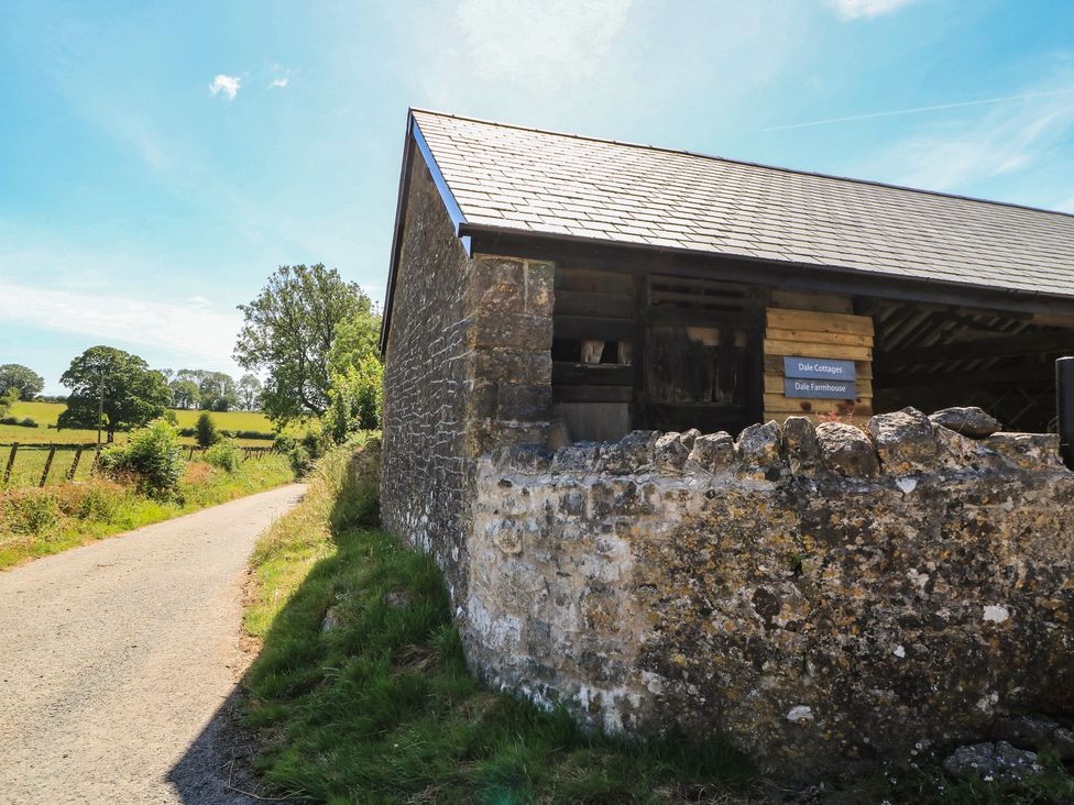 A stone building near a road with a sign at Dale Cottages in Wells