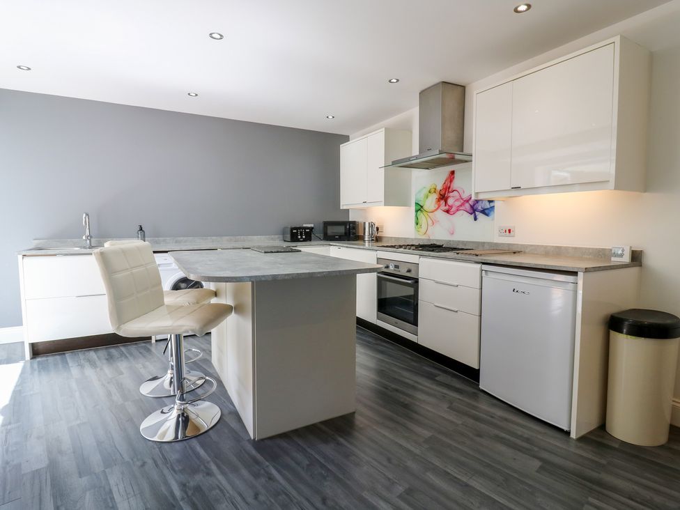 A kitchen with appliances and bar seating at 38 The Parade Walton-On-The-Naze