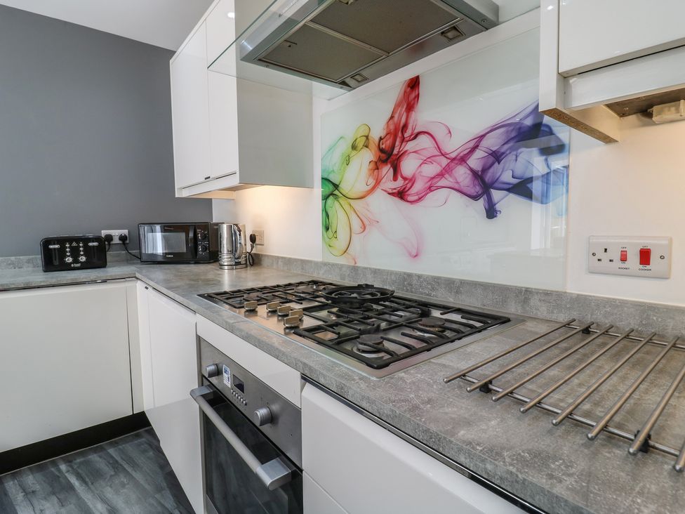 A kitchen with a gas stove and microwave at 38 The Parade Walton-On-The-Naze