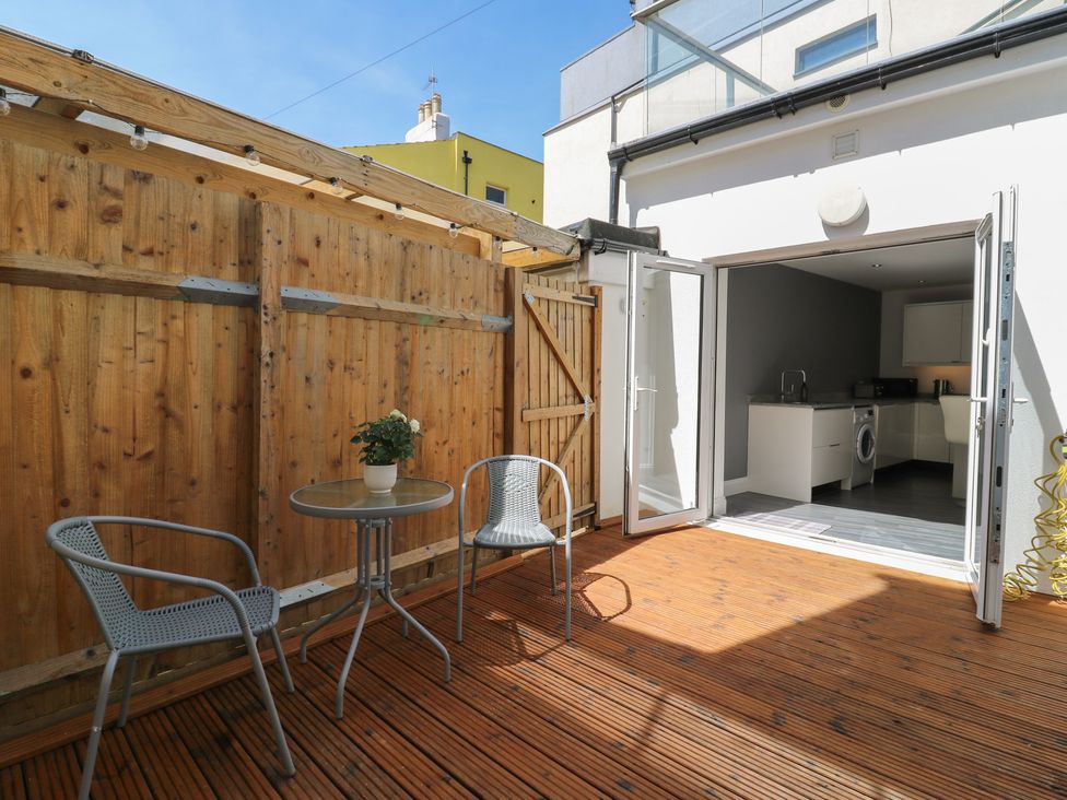 An outdoor space with chairs and a table leading to a kitchen at 38 The Parade Walton-On-The-Naze