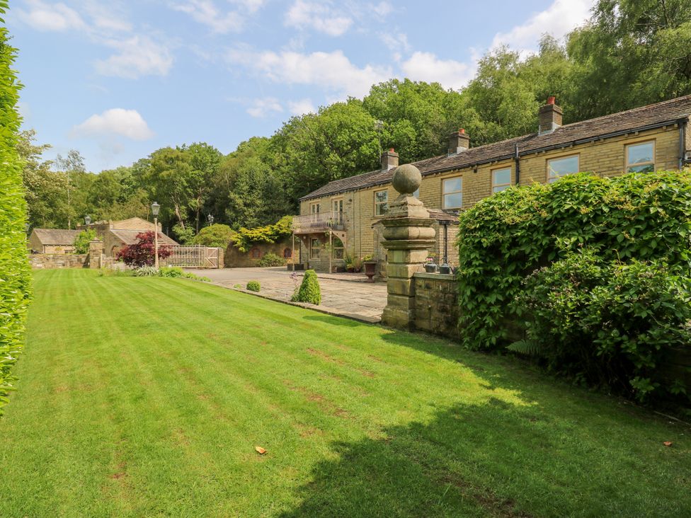 A garden with a house in the background at Woodbottom Farm in Meltham