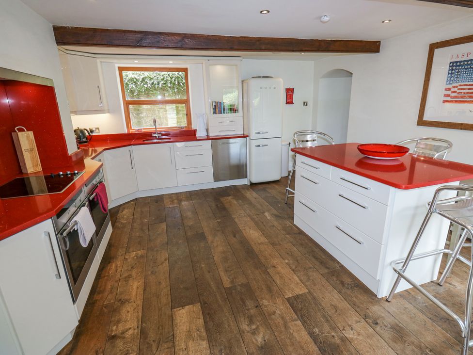 A kitchen with appliances and bar stools at Woodbottom Farm Meltham