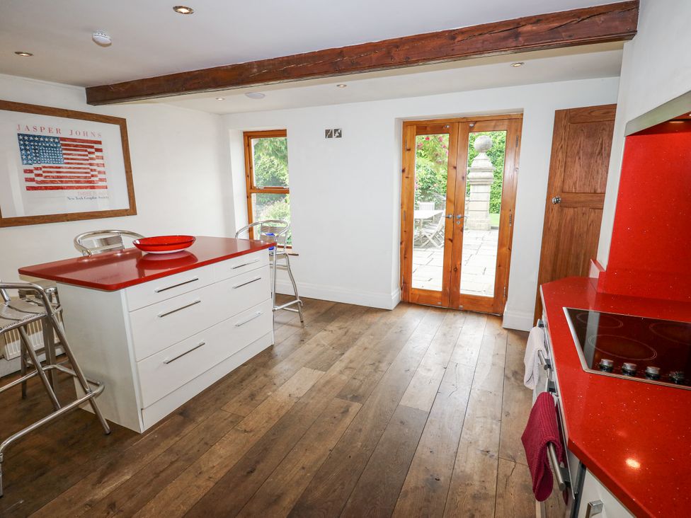 A kitchen with a red island and double doors to the garden at Woodbottom Farm in Meltham