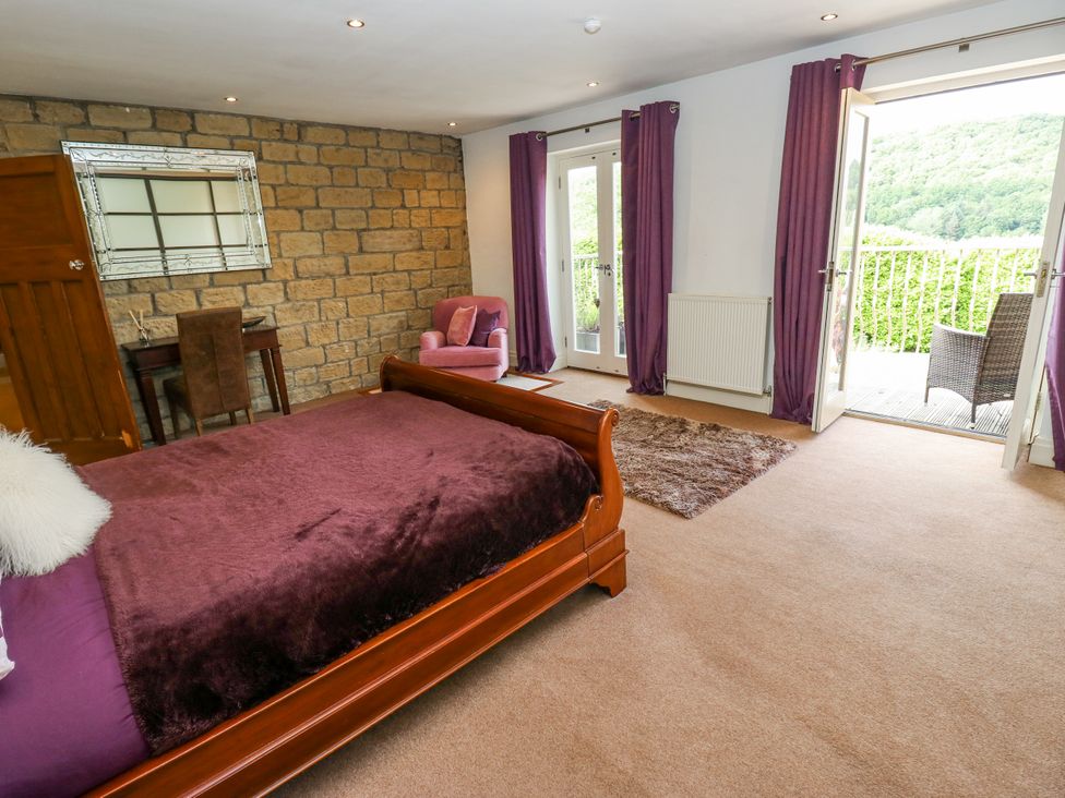 A bedroom with a bed and mirror at Woodbottom Farm in Meltham