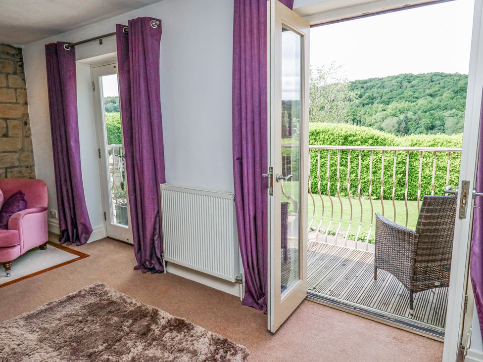 A living room with a chair and open door to a balcony at Woodbottom Farm Meltham