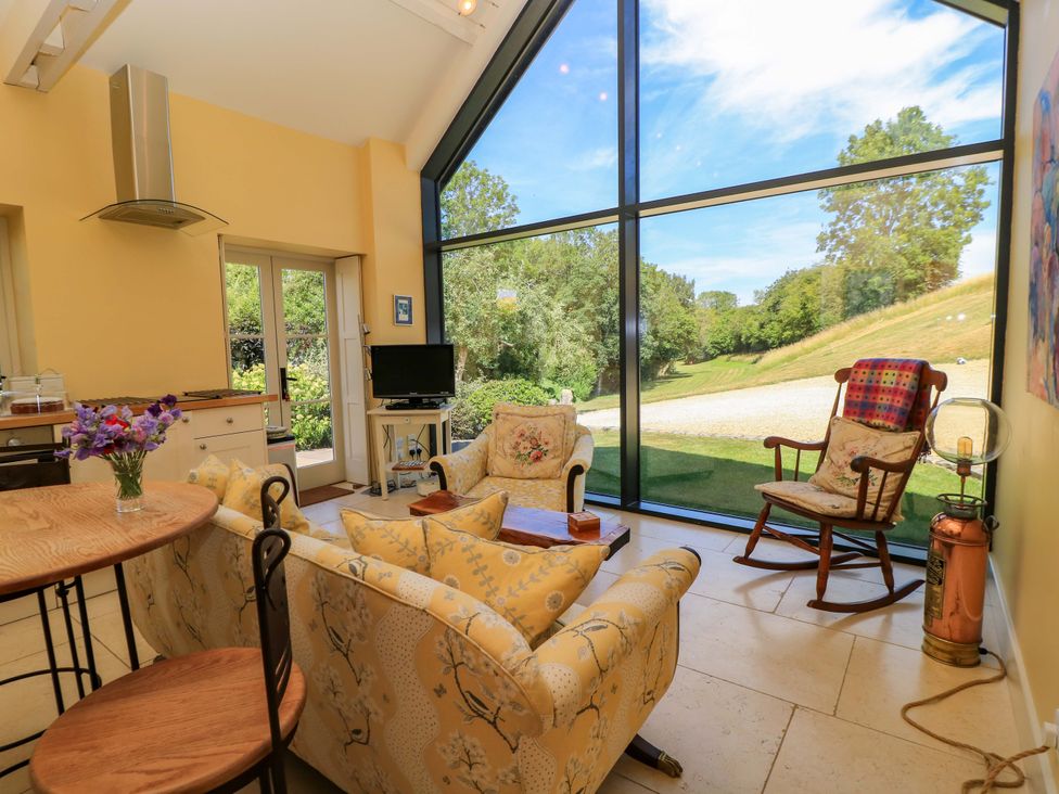 A living room with a large window and seating at Pheasant Cottage in Priston Village, BATH