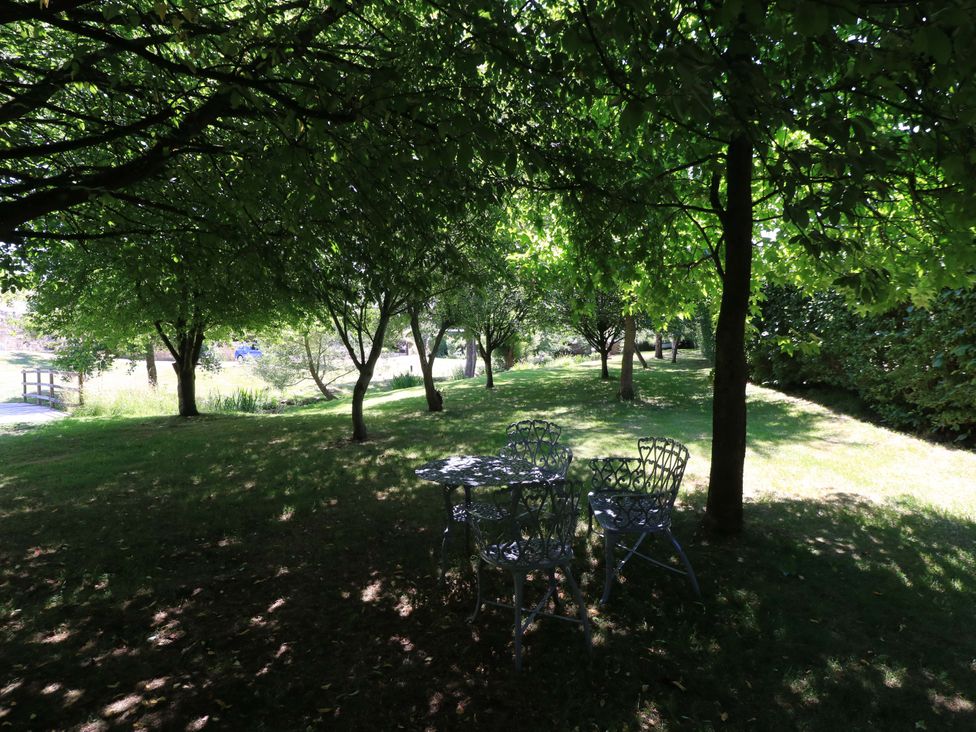A garden with trees and a table with chairs at Pheasant Cottage in Priston Village, BATH