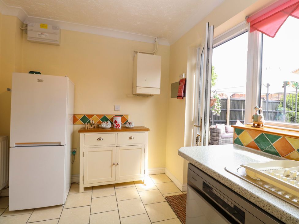 A kitchen with a refrigerator and cupboard at Breydon Cottage in Bradwell near Gorleston-On-Sea