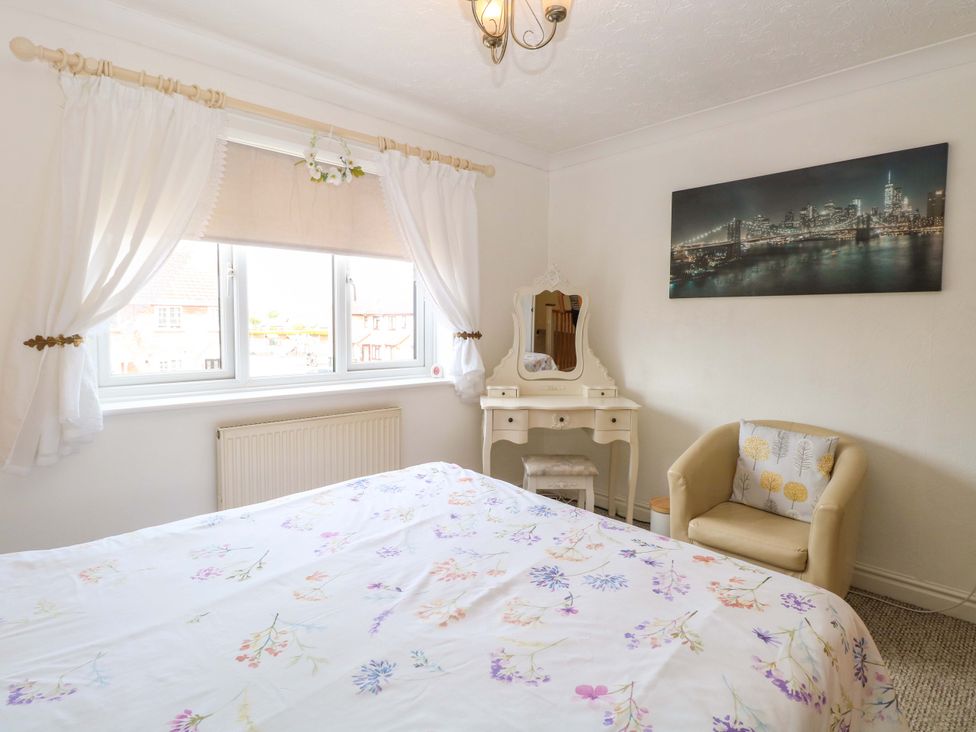 A bedroom with a bed and a dressing table at Breydon Cottage in Bradwell near Gorleston-On-Sea