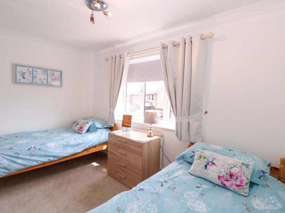 A bedroom with two beds and a nightstand at Breydon Cottage, Bradwell near Gorleston-On-Sea