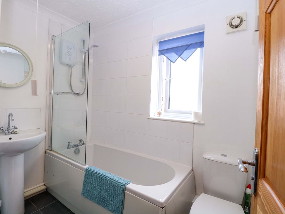 A bathroom with a bathtub, shower, sink, and toilet at Breydon Cottage in Bradwell near Gorleston-On-Sea