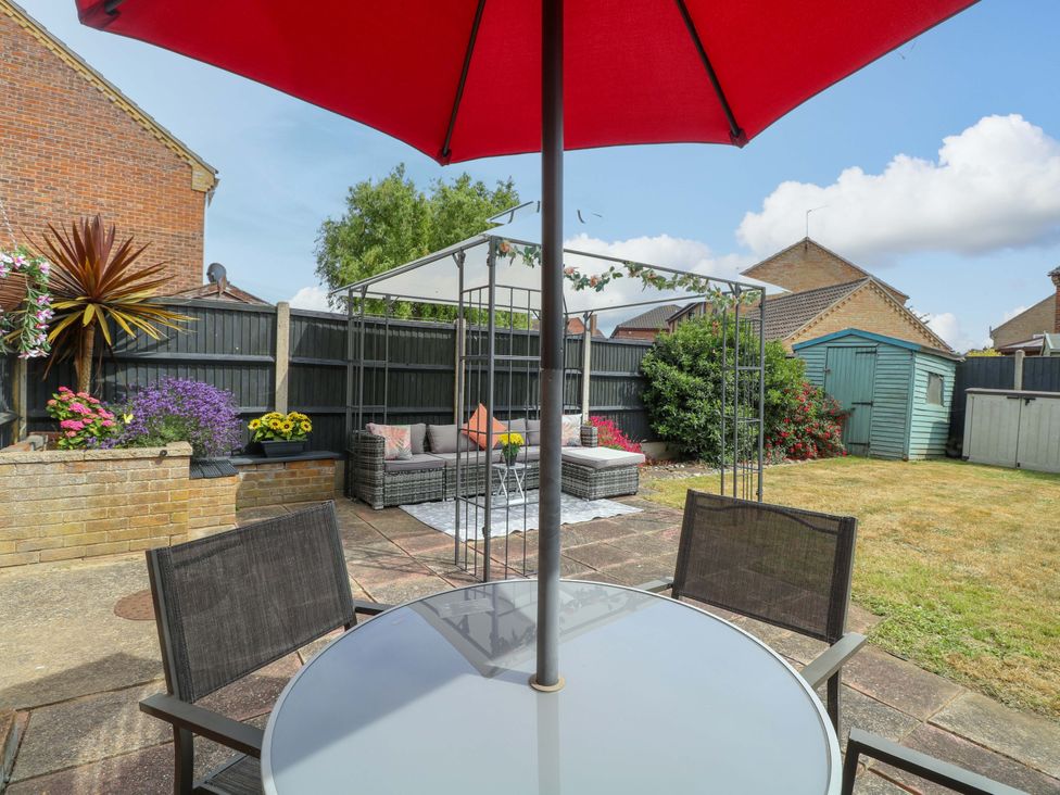 A garden with table, chairs, and a sofa at Breydon Cottage in Bradwell near Gorleston-On-Sea