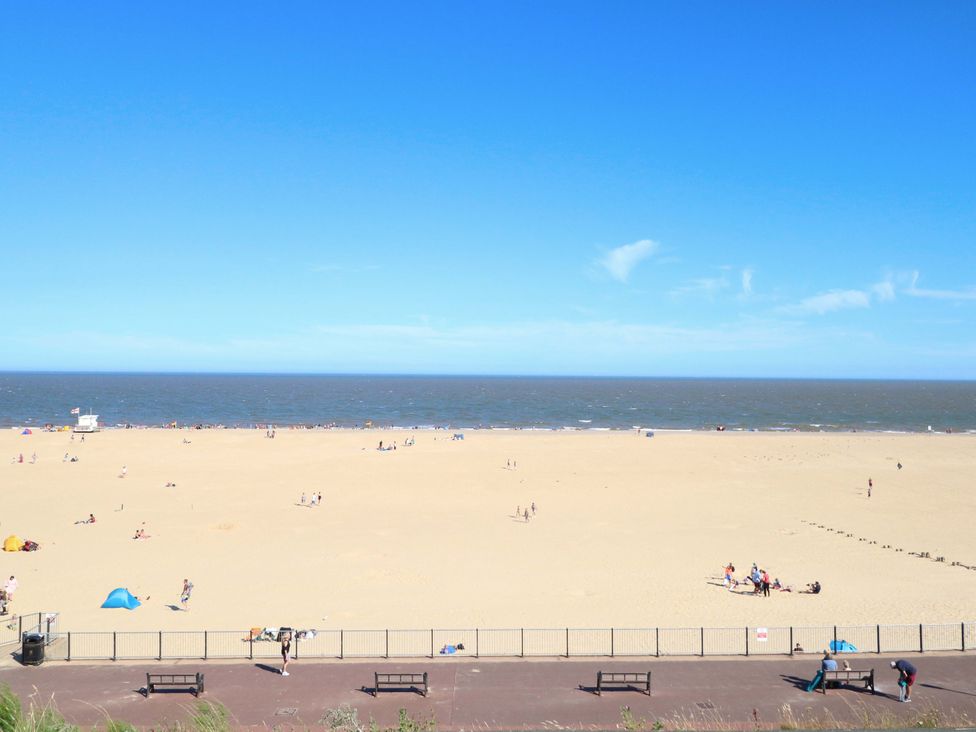 A beach with people and benches at Breydon Cottage Bradwell near Gorleston-On-Sea