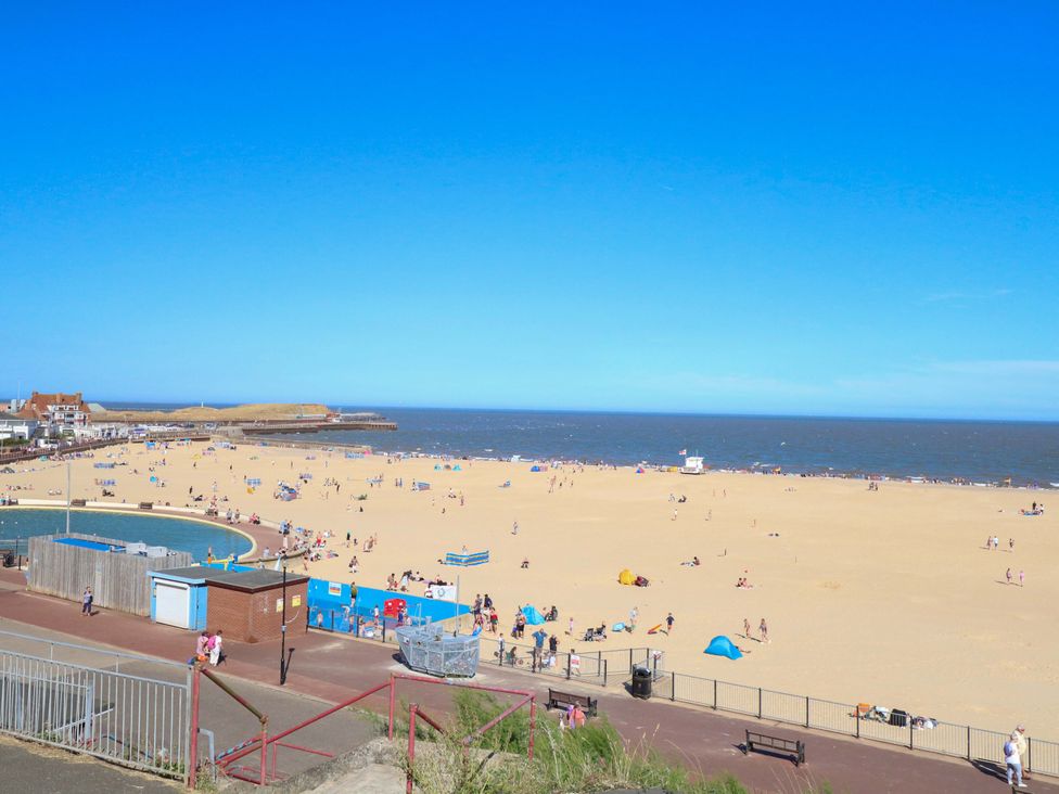A beach with people and sunshades at Breydon Cottage in Bradwell near Gorleston-On-Sea