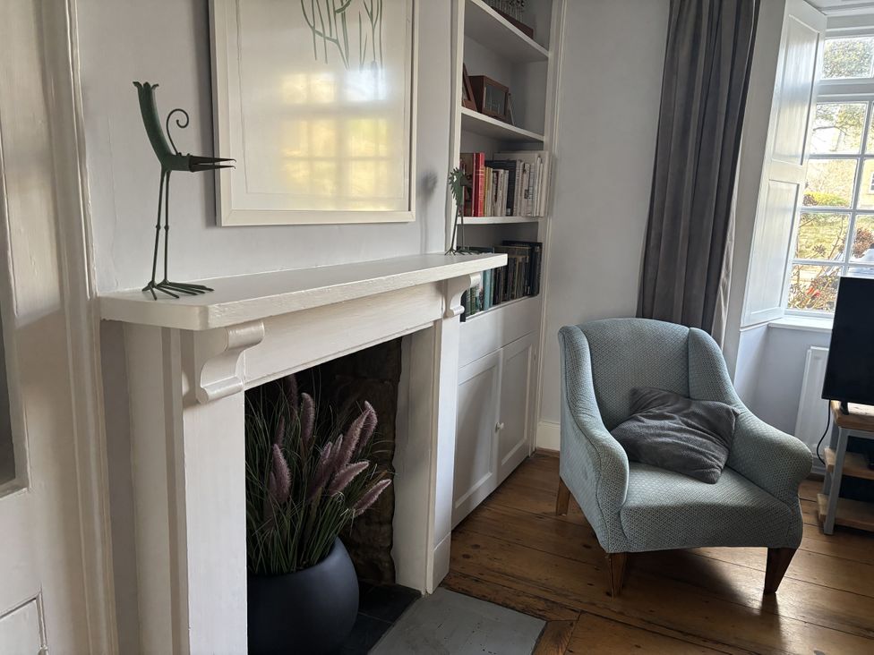 A living room with a fireplace and bookshelf at Brock Cottage in West Bay