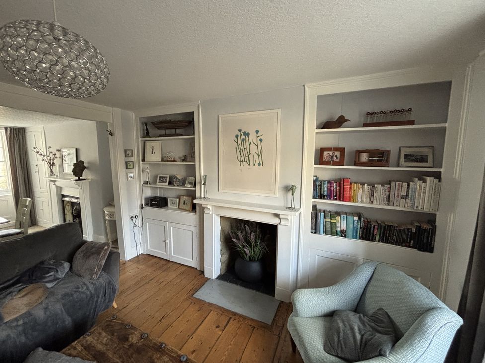 A living room with a sofa and bookshelf at Brock Cottage in West Bay