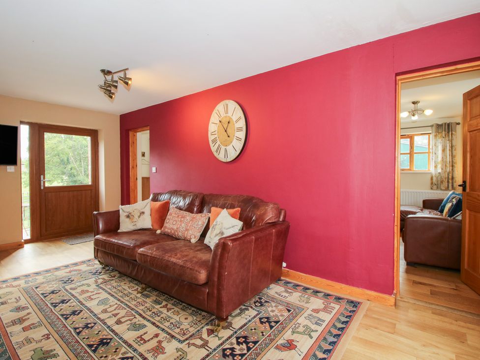 A living room with a sofa and clock at Old Hall Barn 2 Church Stretton
