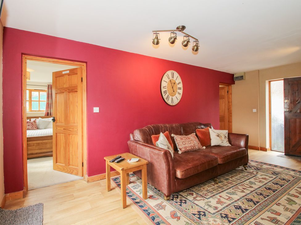 A living room with a sofa and clock at Old Hall Barn 2 Church Stretton