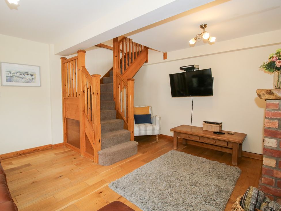 A living room with a staircase and television at Old Hall Barn 2 Church Stretton
