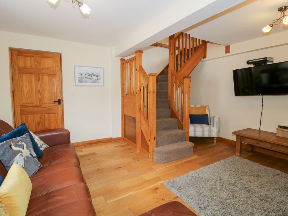 A living room with a staircase and television at Old Hall Barn 2 Church Stretton