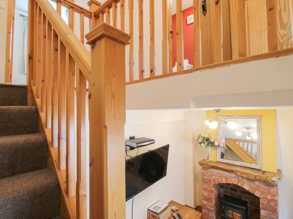 A living room with a staircase and television at Old Hall Barn 2 Church Stretton