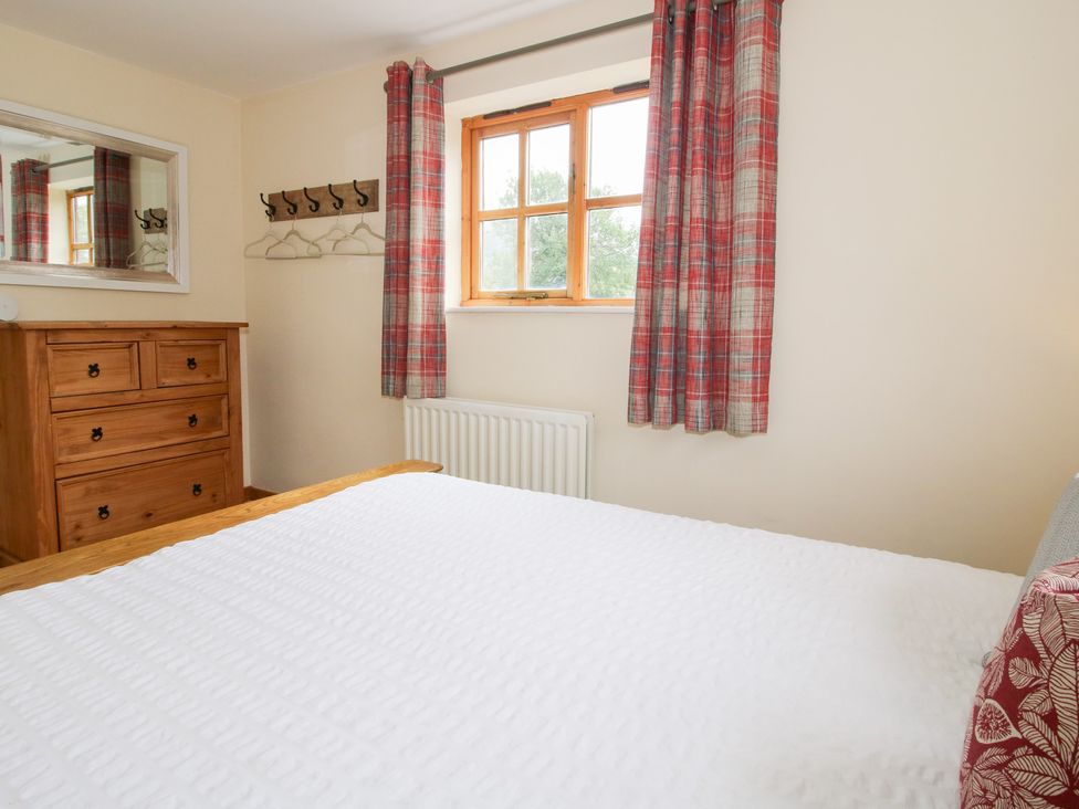 A bedroom with a bed and wooden furniture at Old Hall Barn 2 Church Stretton