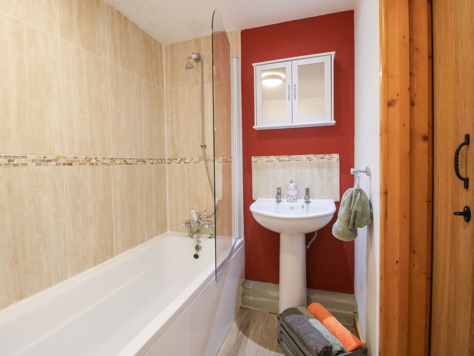 A bathroom with a bathtub, sink, and mirror at Old Hall Barn 2 Church Stretton