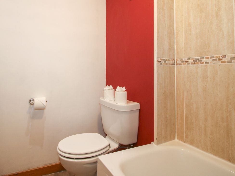 A bathroom featuring a toilet, tissue rolls, and bathtub at Old Hall Barn 2 Church Stretton