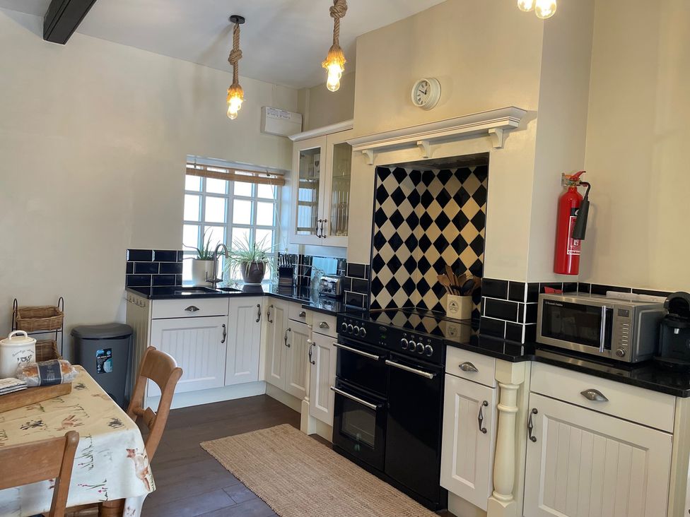 A kitchen with cabinets, oven, and sink at Warren House Cottage in Wragby