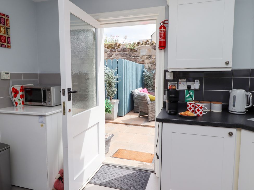 A kitchen with a door leading to an outdoor patio at Hasting Dairy in North Sunderland near Seahouses