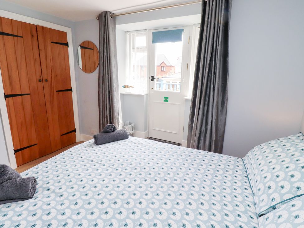 A bedroom with a bed and wooden wardrobe at Hasting Dairy in North Sunderland near Seahouses